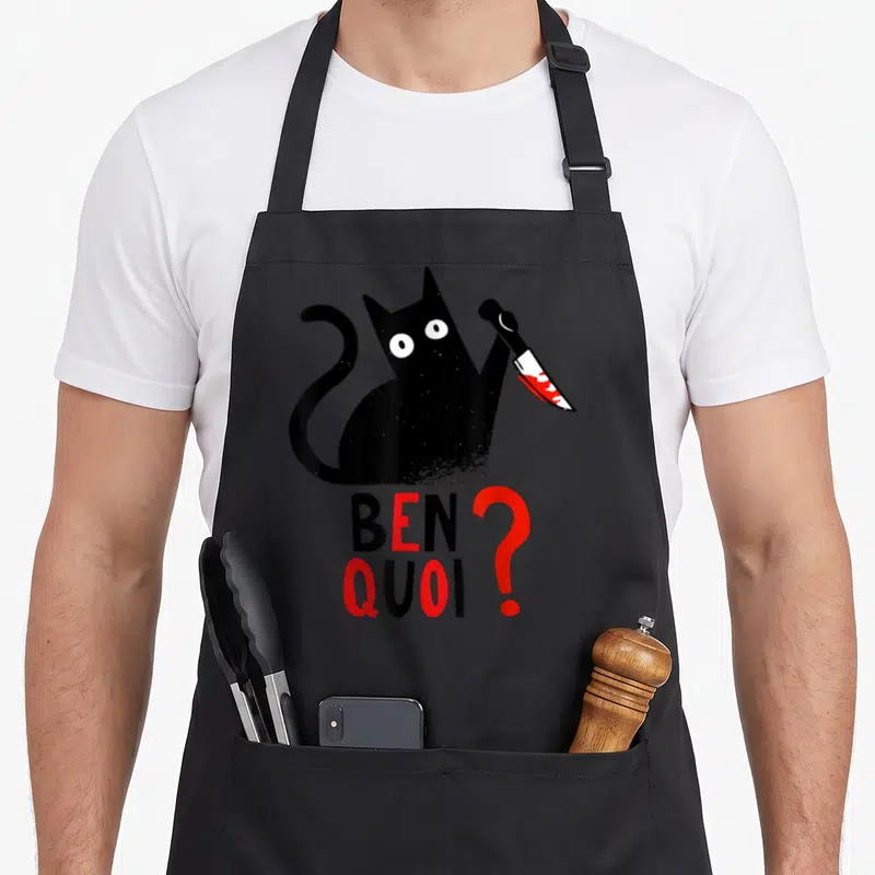 Tablier de cuisine noir avec un chat noir tenant un couteau et le texte ben quoi en rouge et noir.