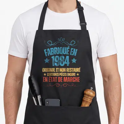 Tablier de cuisine noir avec inscription datant de 1984 original et non restauré en lettres colorées vintage.