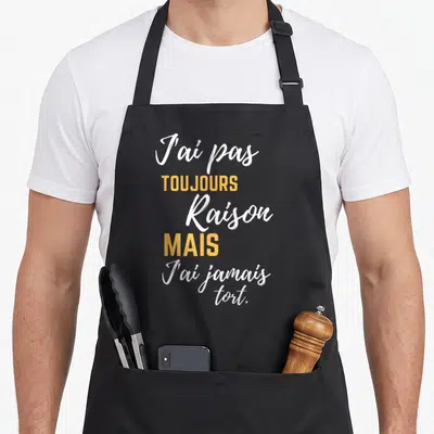 Tablier de cuisine noir avec l'inscription J'ai pas toujours raison mais j'ai jamais tort en typographie blanche et orange.