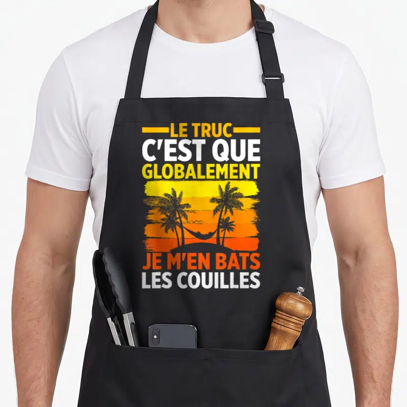 Tablier de cuisine noir avec texte jaune blanc orange et silhouettes de palmiers sur fond de coucher de soleil stylisé.