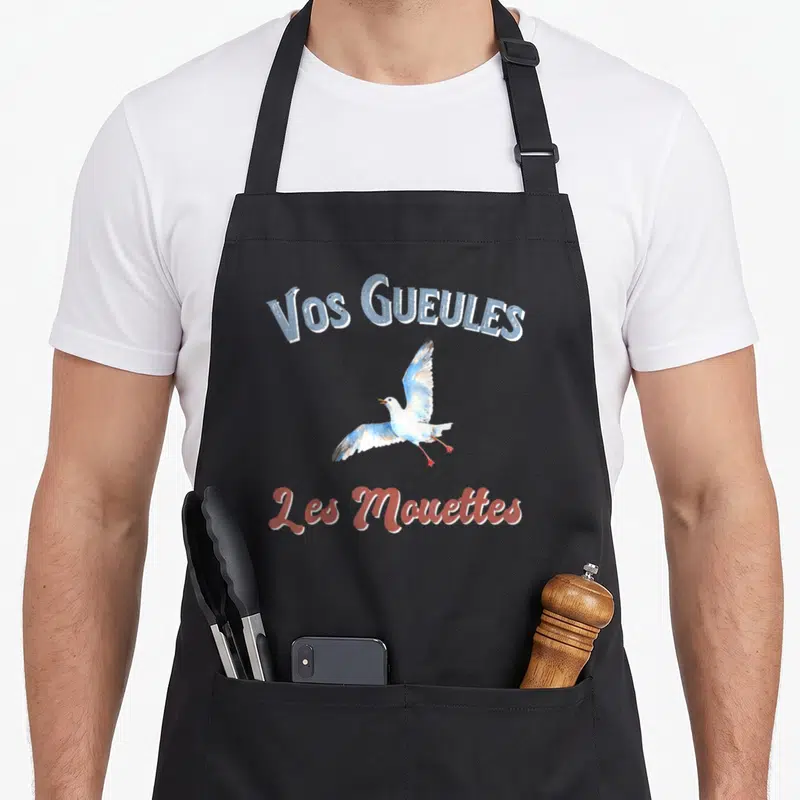 Tablier de cuisine noir avec illustration d'une mouette et texte vos gueules les mouettes imprimé en bleu et rouge.