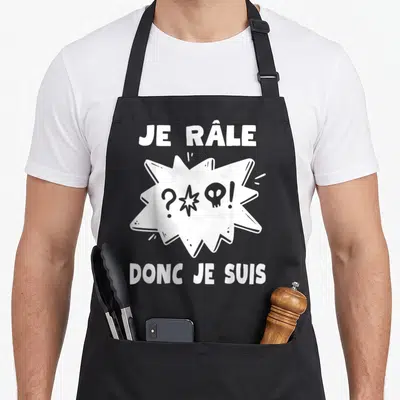 Tablier de cuisine noir avec inscription blanche Je Râle Donc Je Suis et une illustration de bulle de dialogue stylisée.