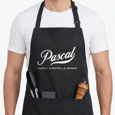 Tablier de cuisine noir avec inscription blanche Pascal l'homme le mythe la légende en typographie stylisée.