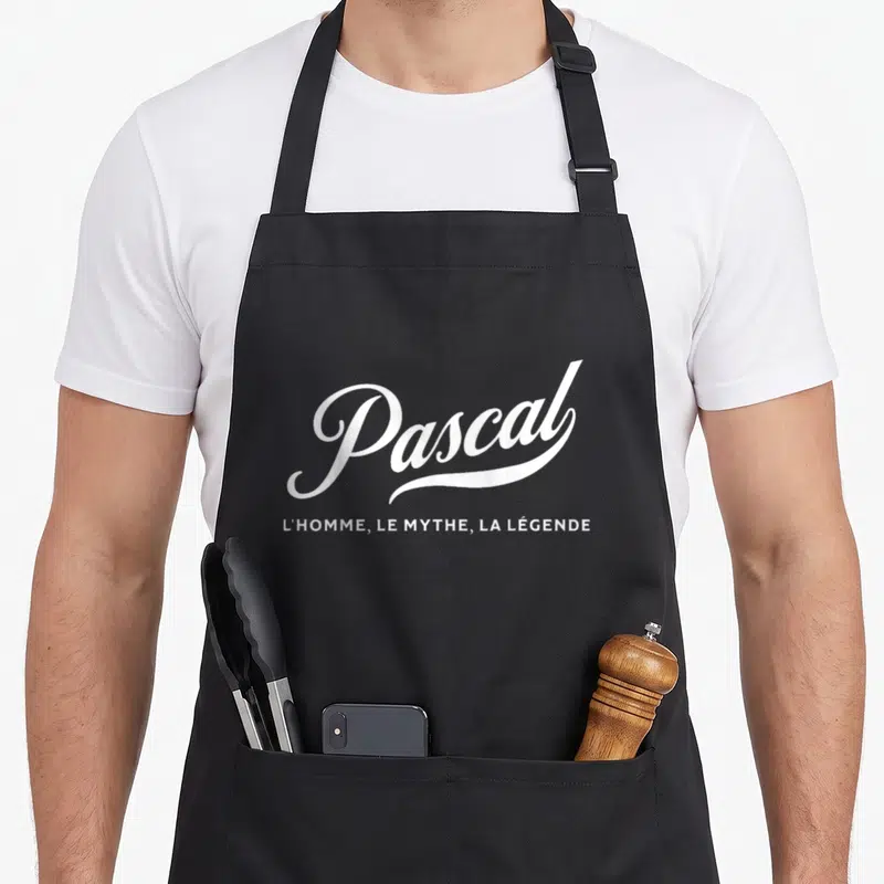 Tablier de cuisine noir avec inscription blanche Pascal l'homme le mythe la légende en typographie stylisée.
