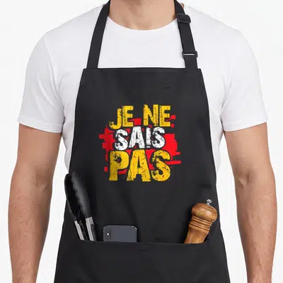 Tablier de cuisine noir avec inscription je ne sais pas en lettres jaunes et blanches sur fond rouge texturé.