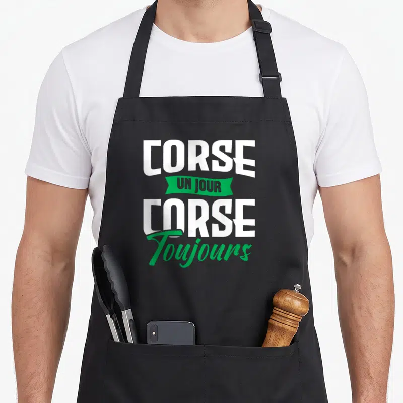 Tablier de cuisine noir avec l'inscription blanche et verte Corse un jour corse toujours en typographie stylisée.