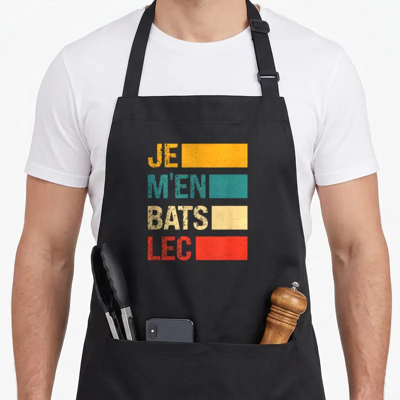 Tablier de cuisine noir avec inscription colorée Je m'en bats lec sur fond uni.