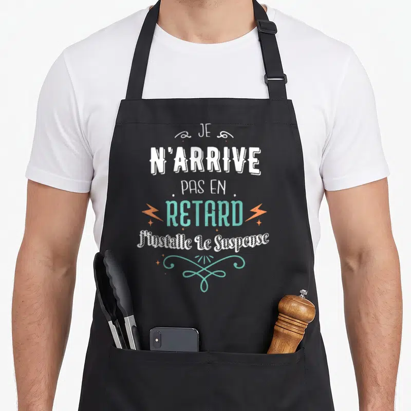 Tablier de cuisine noir avec inscription Je n'arrive pas en retard j'installe le suspense en blanc et turquoise orné d'éclairs orange.
