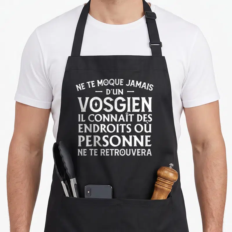 Tablier de cuisine noir avec l'inscription blanche Ne te moque jamais d'un Vosgien et son slogan humoristique.