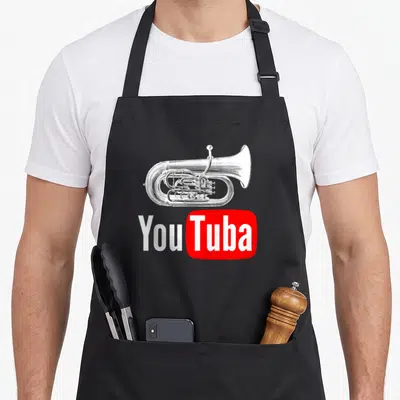 Tablier de cuisine noir avec illustration d'un euphonium et le texte You Tuba en blanc sur fond rouge.