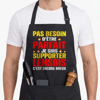 Tablier de cuisine noir avec inscription jaune et rouge « Pas besoin d'être parfait je suis supporter lensois c'est encore mieux » orné de petites flammes.