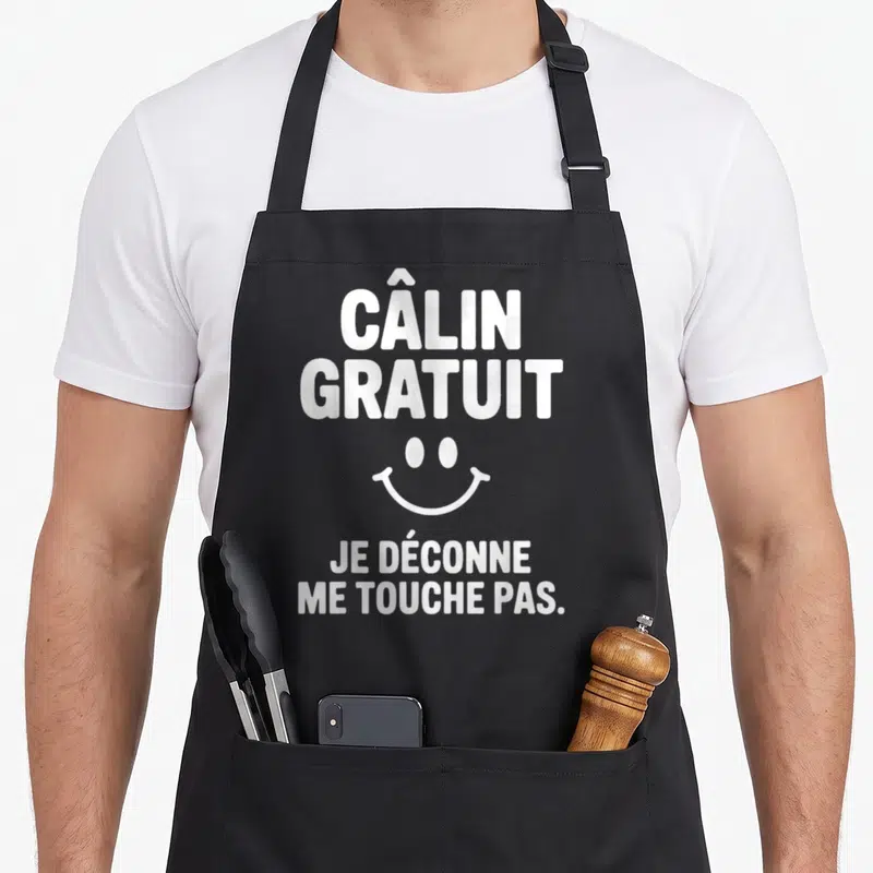 Tablier de cuisine noir avec le texte câlin gratuit je déconne me touche pas et un smiley blanc.