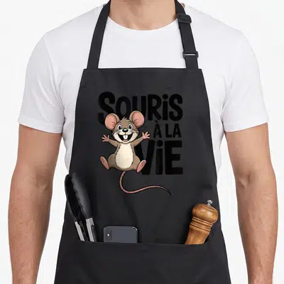 Tablier de cuisine noir avec un dessin de souris marron aux oreilles roses et le texte SOURIS À LA VIE en grosses lettres noires.