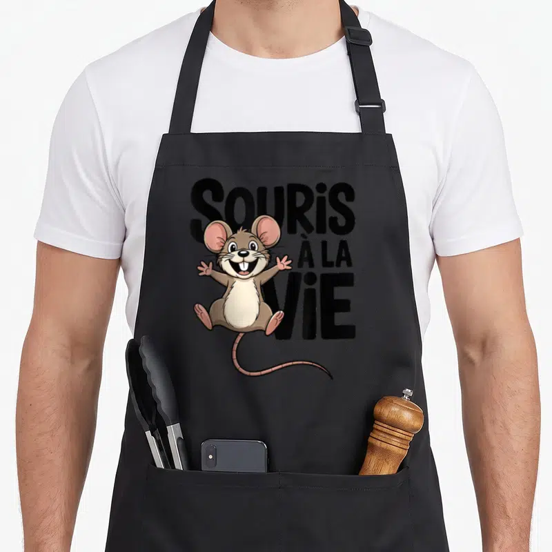 Tablier de cuisine noir avec un dessin de souris marron aux oreilles roses et le texte SOURIS À LA VIE en grosses lettres noires.