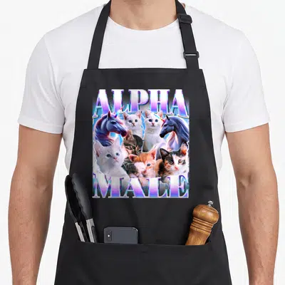 Tablier de cuisine noir avec illustration de chats et licornes sous les mots Alpha Male en lettres colorées.