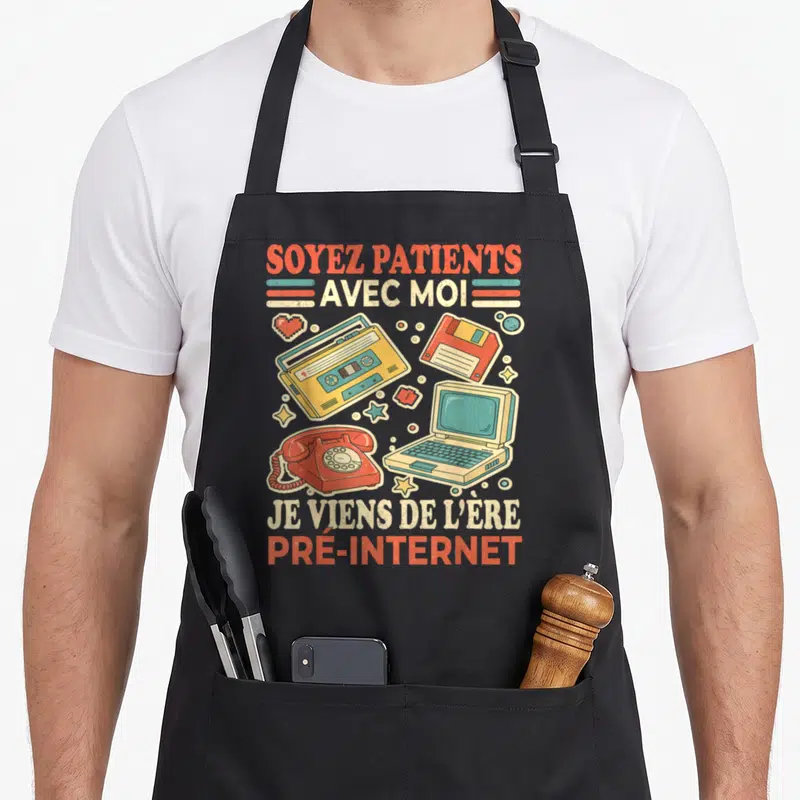 Tablier de cuisine noir avec illustration retro d'un téléphone rotatif, cassette et ordinateur portable ancien.