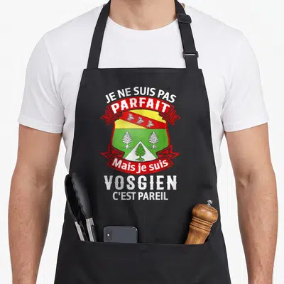 Tablier de cuisine noir avec un blason vert et rouge portant la citation Je ne suis pas parfait mais je suis Vosgien c'est pareil.