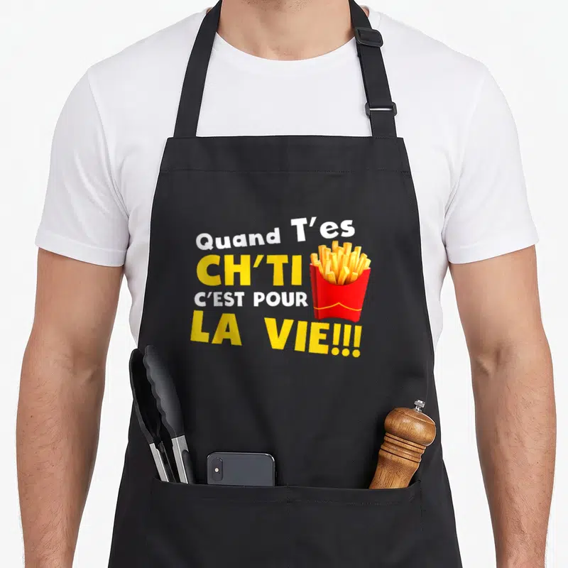 Tablier de cuisine noir avec inscription Quand t'es ch'ti c'est pour la vie et illustration de frites dans une boîte rouge.
