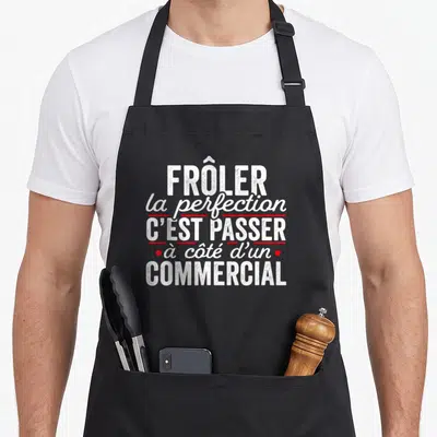 Tablier de cuisine noir avec l'inscription blanche et rouge frôler la perfection c'est passer à côté d'un commercial
