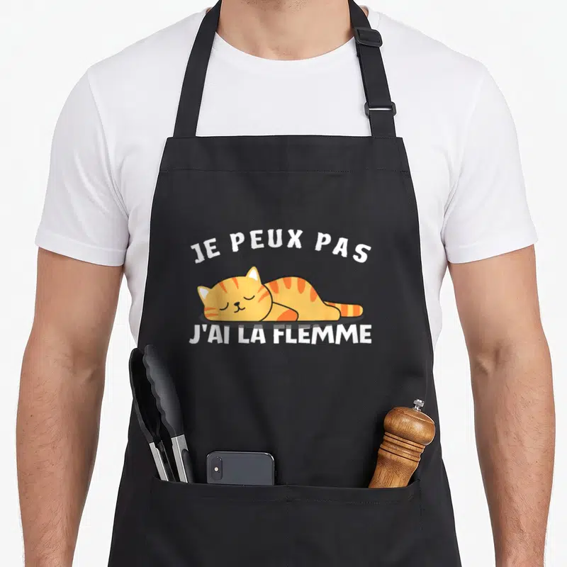 Tablier de cuisine noir avec un chat orange dormant et le texte je peux pas j'ai la flemme imprimé en blanc.