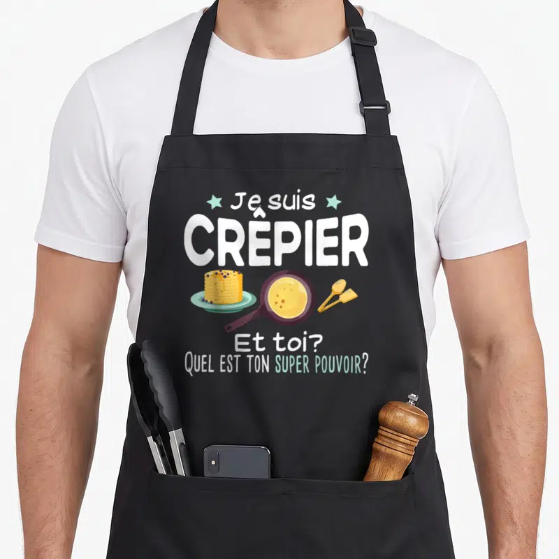 Tablier de cuisine noir avec texte Je suis crêpier et toi quel est ton super pouvoir illustré d'une gaufre et d'une poêle.