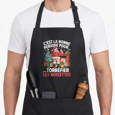Tablier de cuisine noir avec illustration de Santa nu-torse et texte torréfier les noisettes.
