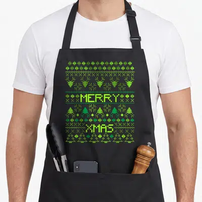 Tablier de cuisine noir avec motif pixel vert Merry Xmas rennes et sapins de Noël.
