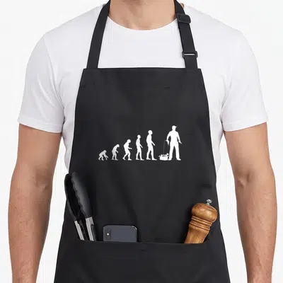 Tablier de cuisine noir avec illustration blanche représentant l'evolution humaine se terminant par un bricoleur tenant une boîte à outils et un outil.