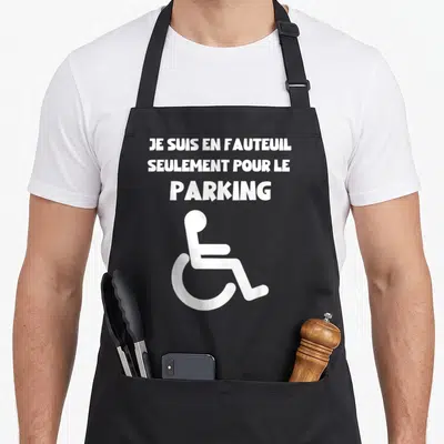 Tablier de cuisine noir avec texte blanc je suis en fauteuil seulement pour le parking et un pictogramme de fauteuil roulant.