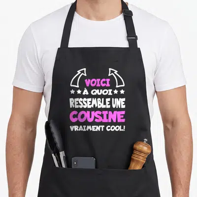 Tablier de cuisine noir avec inscription Voici à quoi ressemble une cousine vraiment cool en lettres roses et blanches.