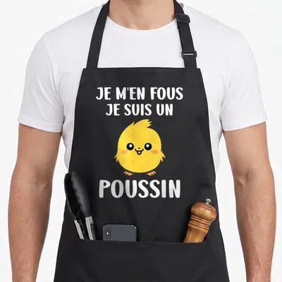 Tablier de cuisine noir avec un poussin jaune souriant et le texte blanc Je m'en fous je suis un poussin