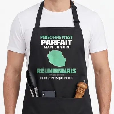Tablier de cuisine noir avec carte verte de l'île et texte blanc Personne n'est parfait mais je suis Réunionnais et c'est presque pareil