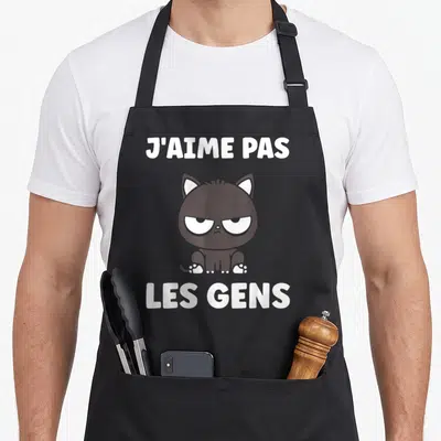 Tablier de cuisine noir avec un chat noir grognon et le texte blanc J'aime pas les gens imprimé au centre.