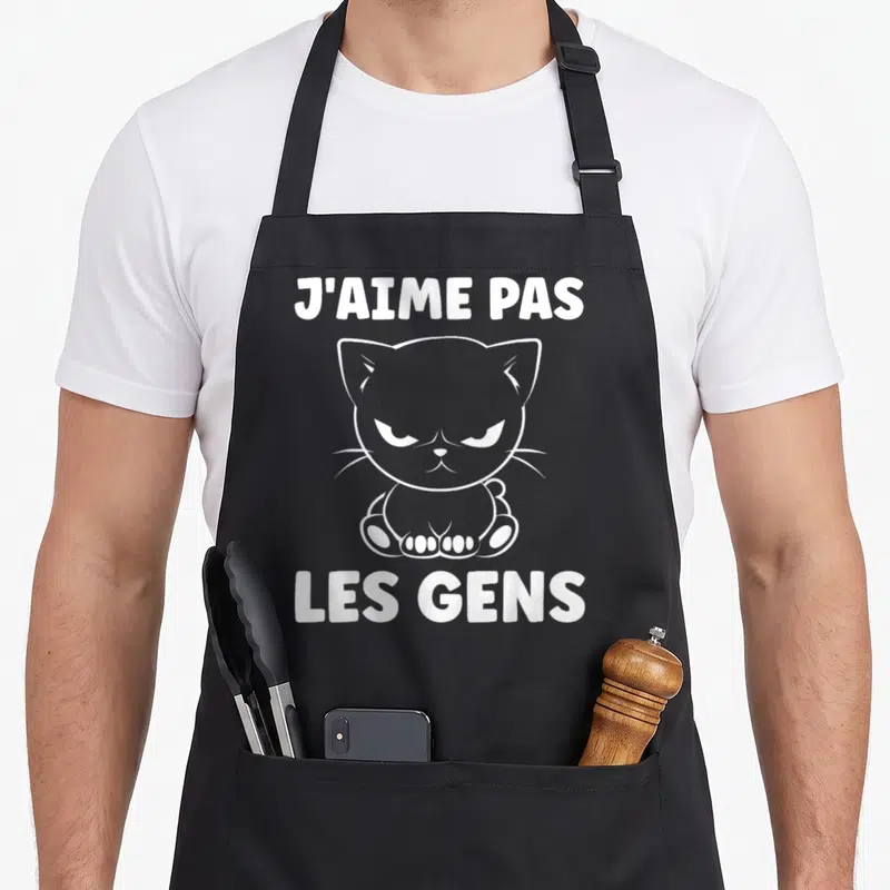 Tablier de cuisine noir avec illustration d'un chat grognon blanc et le texte j'aime pas les gens imprimé en lettres capitales.