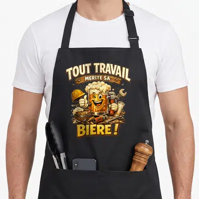 Tablier de cuisine noir avec illustration d'un verre de bière souriant entouré d'outils de travail et du texte tout travail mérite sa biere