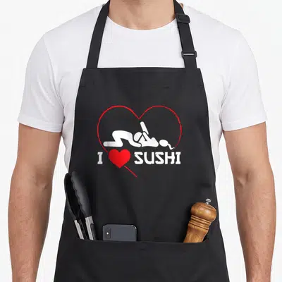 Tablier de cuisine noir avec un cœur rouge et une silhouette blanche sous le texte I Love Sushi.