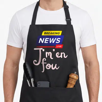 Tablier de cuisine noir avec le logo Breaking News Live et la phrase J'm'en fou en lettres roses stylisées.