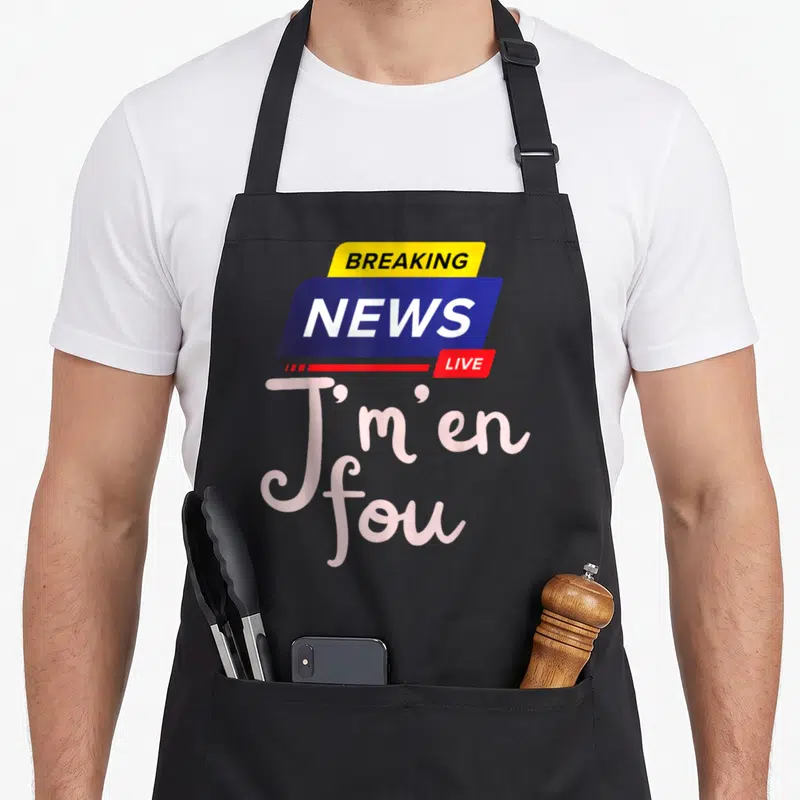 Tablier de cuisine noir avec le logo Breaking News Live et la phrase J'm'en fou en lettres roses stylisées.
