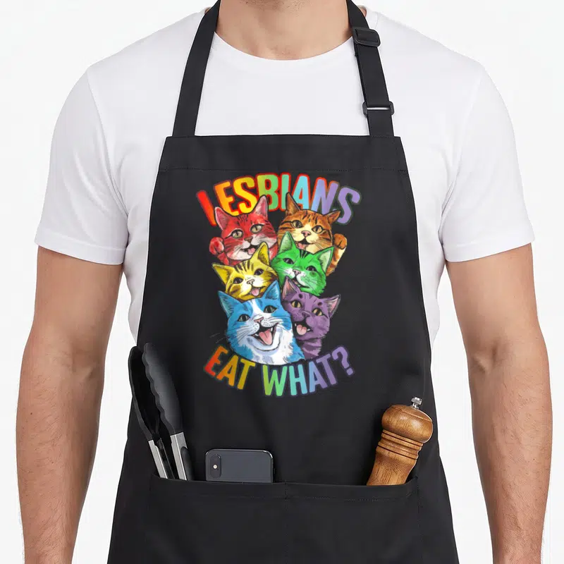 Tablier de cuisine noir avec six chats colorés et le texte Lesbians Eat What en arc-en-ciel.