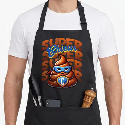Tablier de cuisine noir avec illustration d'une caca en super-héros et texte super chieur en arrière-plan orange et bleu.