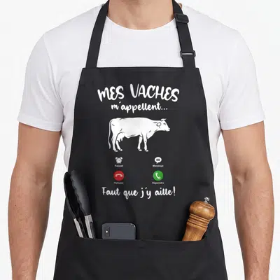 Tablier de cuisine noir avec une vache blanche et texte humoristique sur appels téléphoniques.