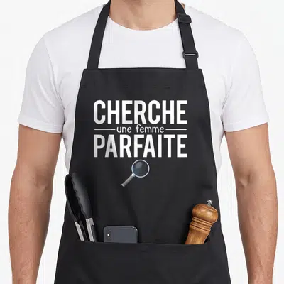 Tablier de cuisine noir avec texte cherche une femme parfaite et illustration d'une loupe grise.