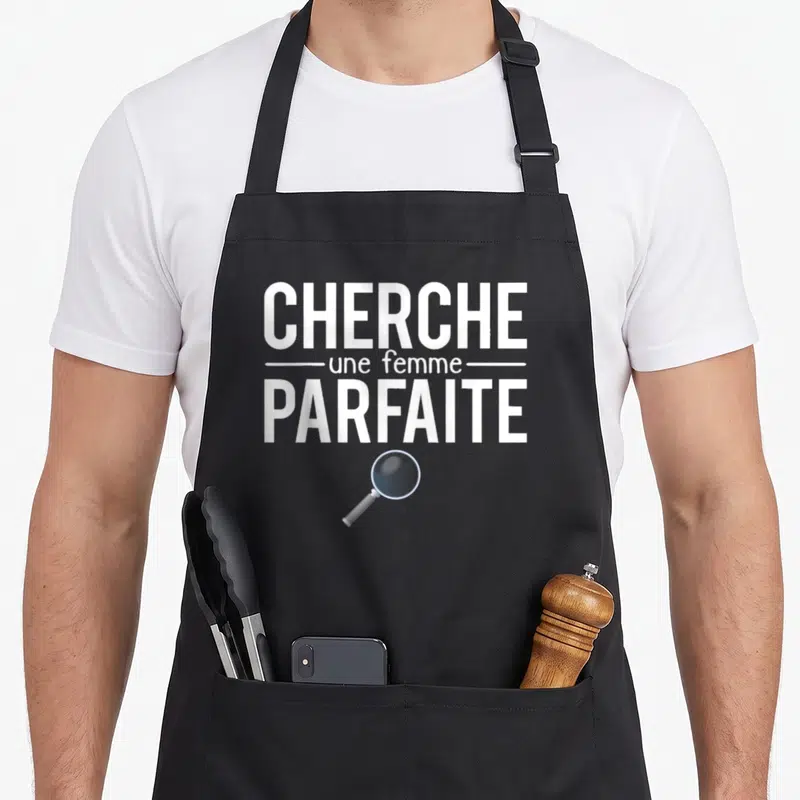 Tablier de cuisine noir avec texte cherche une femme parfaite et illustration d'une loupe grise.
