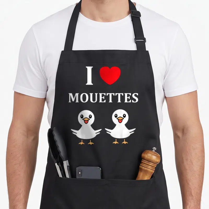 Tablier de cuisine noir avec deux mouettes blanches riantes, un cœur rouge et le texte I MOUETTES imprimé en blanc.