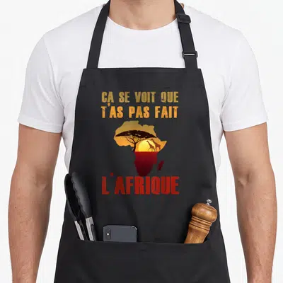 Tablier de cuisine noir avec carte Afrique, girafes et phrase ça se voit que t'as pas fait l'Afrique en orange et rouge.