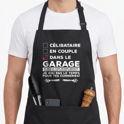 Tablier de cuisine noir avec inscription blanche dans le garage et deux clés anglaises en bas.