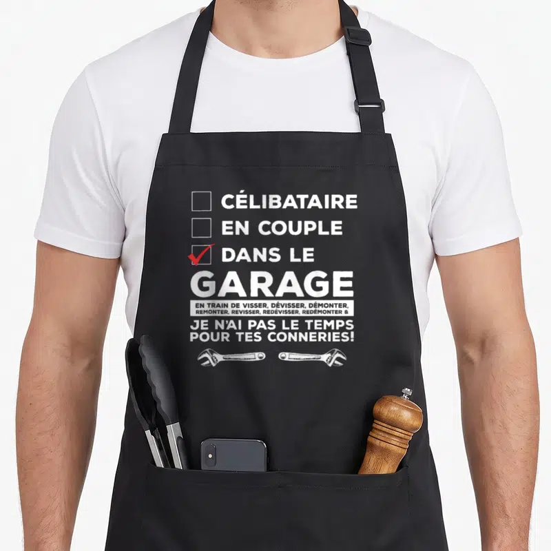 Tablier de cuisine noir avec inscription blanche dans le garage et deux clés anglaises en bas.