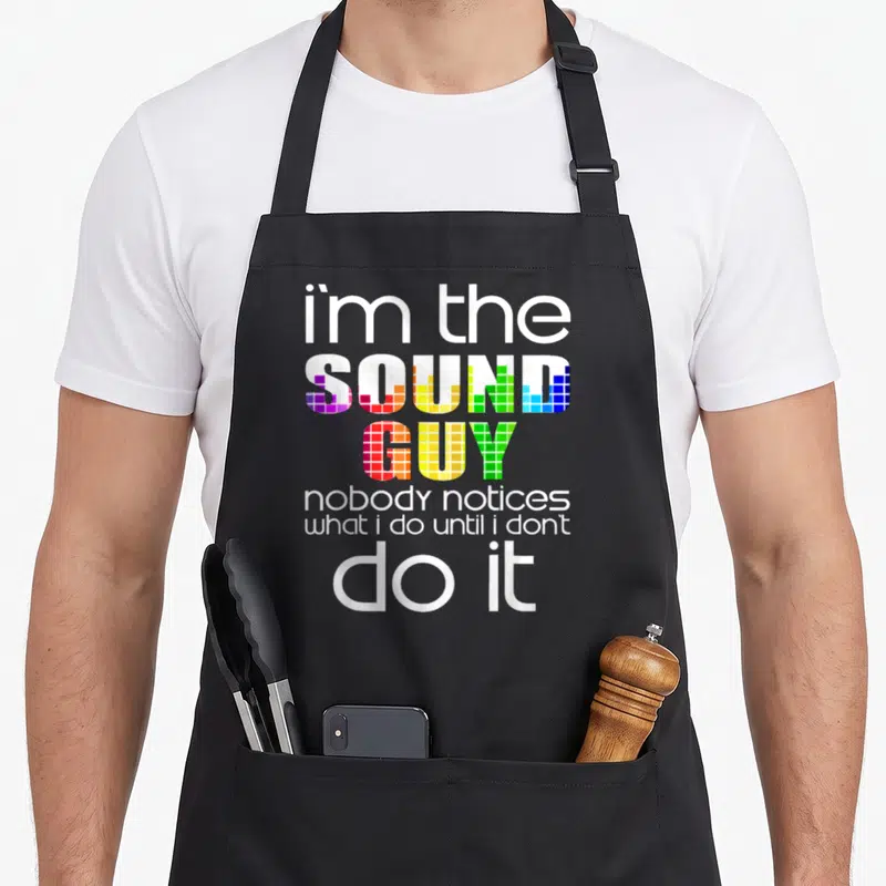 Tablier de cuisine noir avec le texte Im the Sound Guy nobody notices what i do until i dont do it imprimé en couleurs vives.