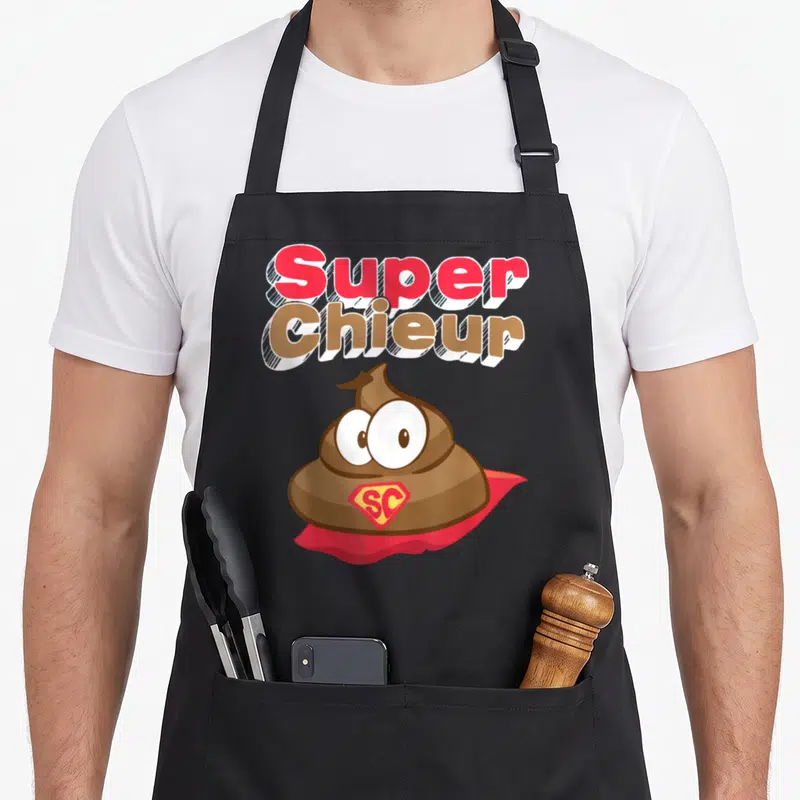 Tablier de cuisine noir avec illustration d'un caca en super-héros et texte Super Chieur en lettres colorisées.