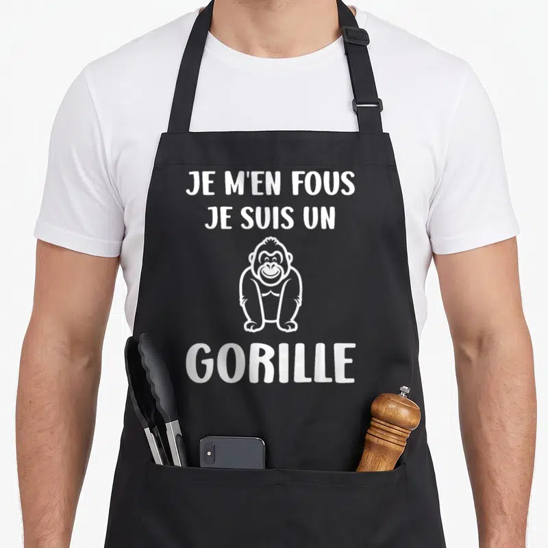 Tablier de cuisine noir avec inscription blanche Je m'en fous je suis un gorille et un dessin de singe souriant.